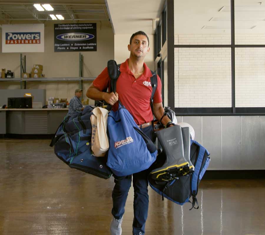 safety professional carrying multiple inspection and safety equipment bags
